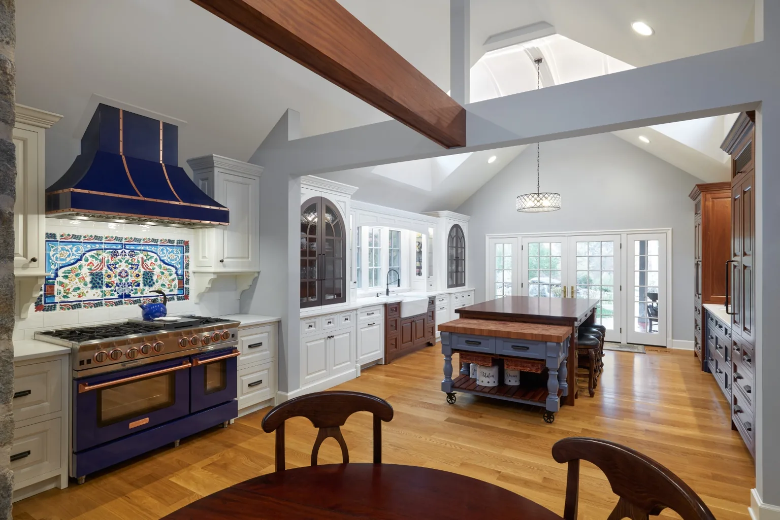 Chester, PA kitchen addition with a cobalt blue and copper range, exposed stone wall, vaulted beamed ceiling, and a mahogany butcher-block island