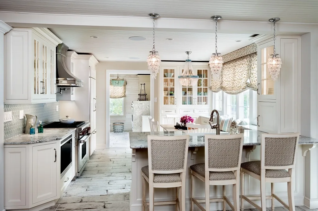 Churchville kitchen after renovation with bright white custom cabinetry, a center island with patterned stools, three beaded chandeliers, a beadboard ceiling, and whitewashed plank floors